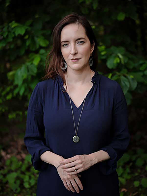 Rebecca Makkai author photo A woman standing while wearing a blue blouse.