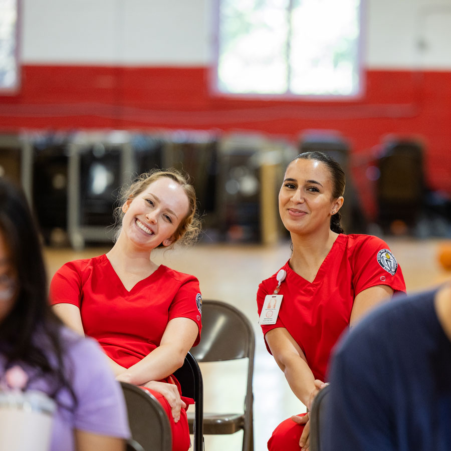 Two nursing students smiling towards the camera during a blood drive.