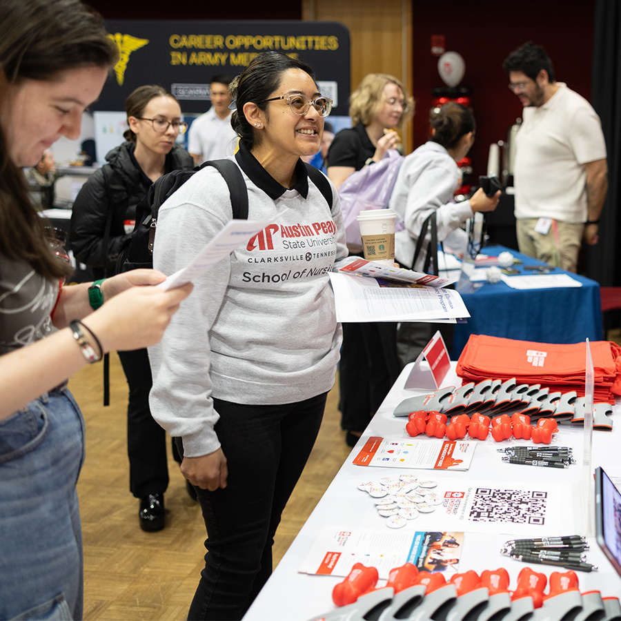Students talking to employeers during a career fair in front of a table of AP themed promo items.