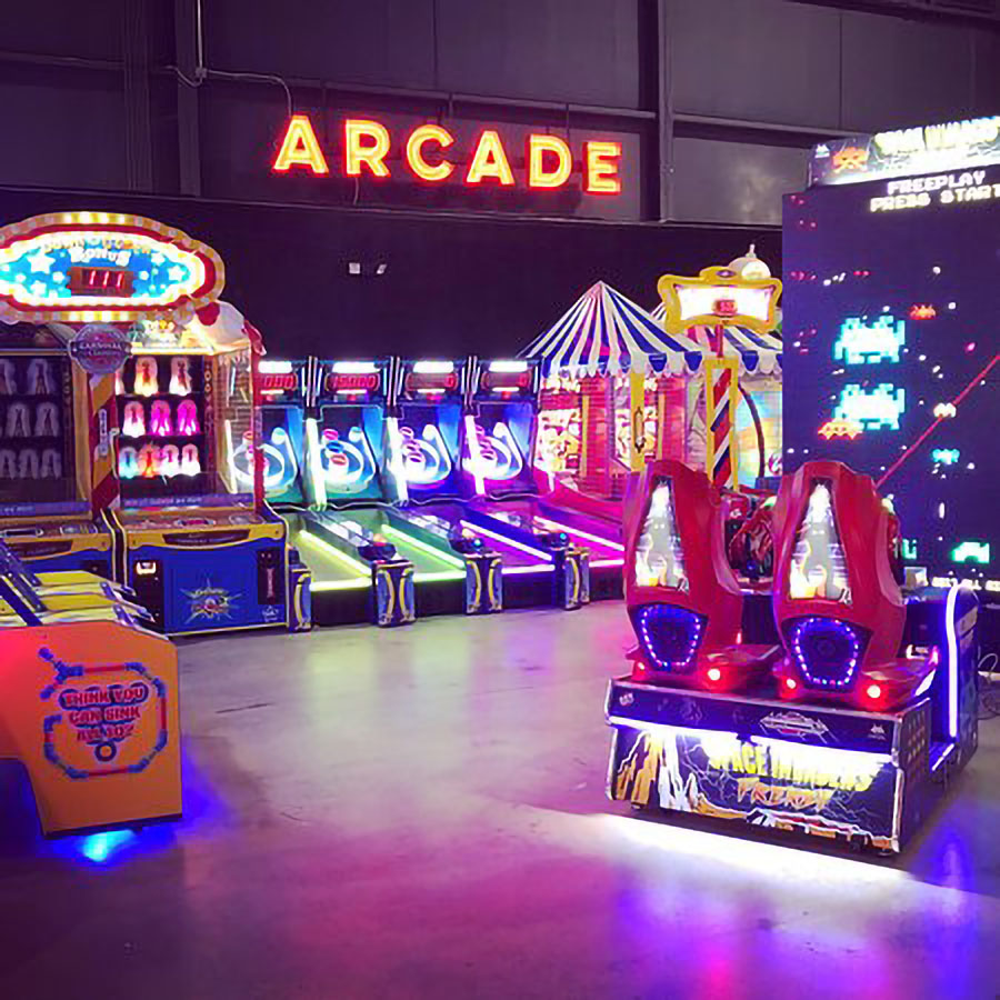 The City Forum's Arcade filled with brightly colored and lit up arcade games in a dark room and a large "ARCADE" neon sign on the wall above the games.