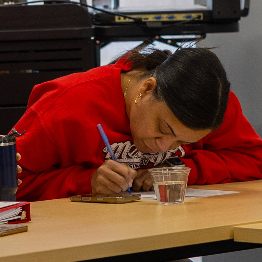 A student hunched over a desk writing on paper.