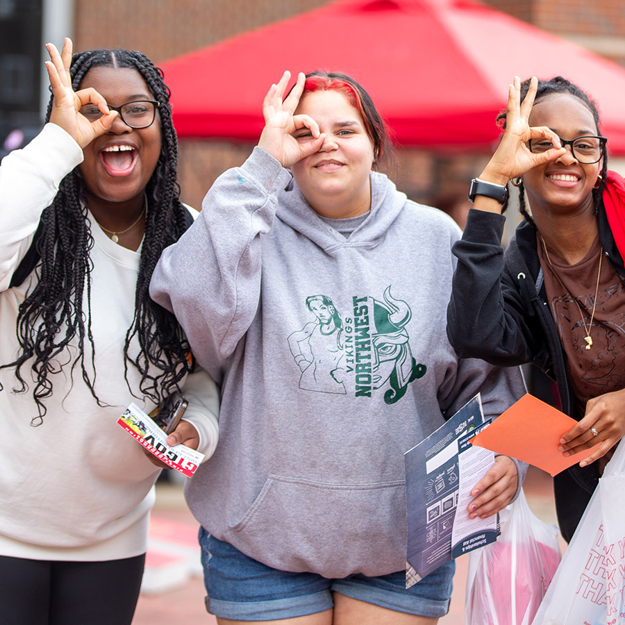 A group of first-year students holding up the monocle sign over their eyes and smiling for the camera.