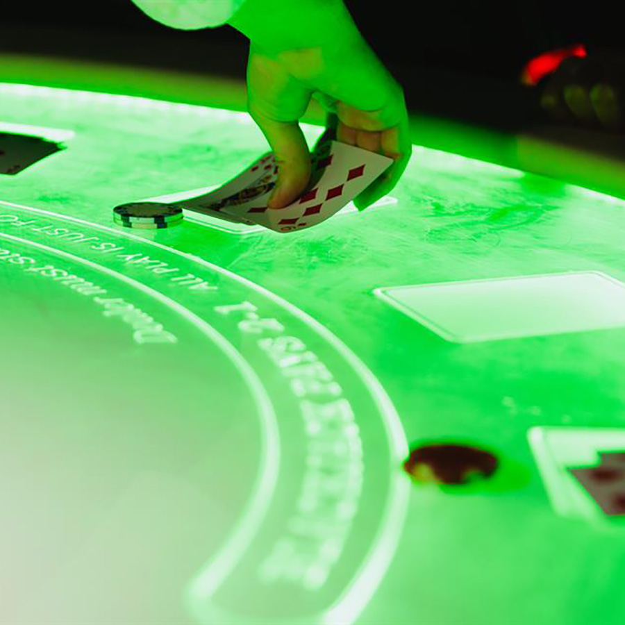 Green glowing poker table with a hand laying down cards.