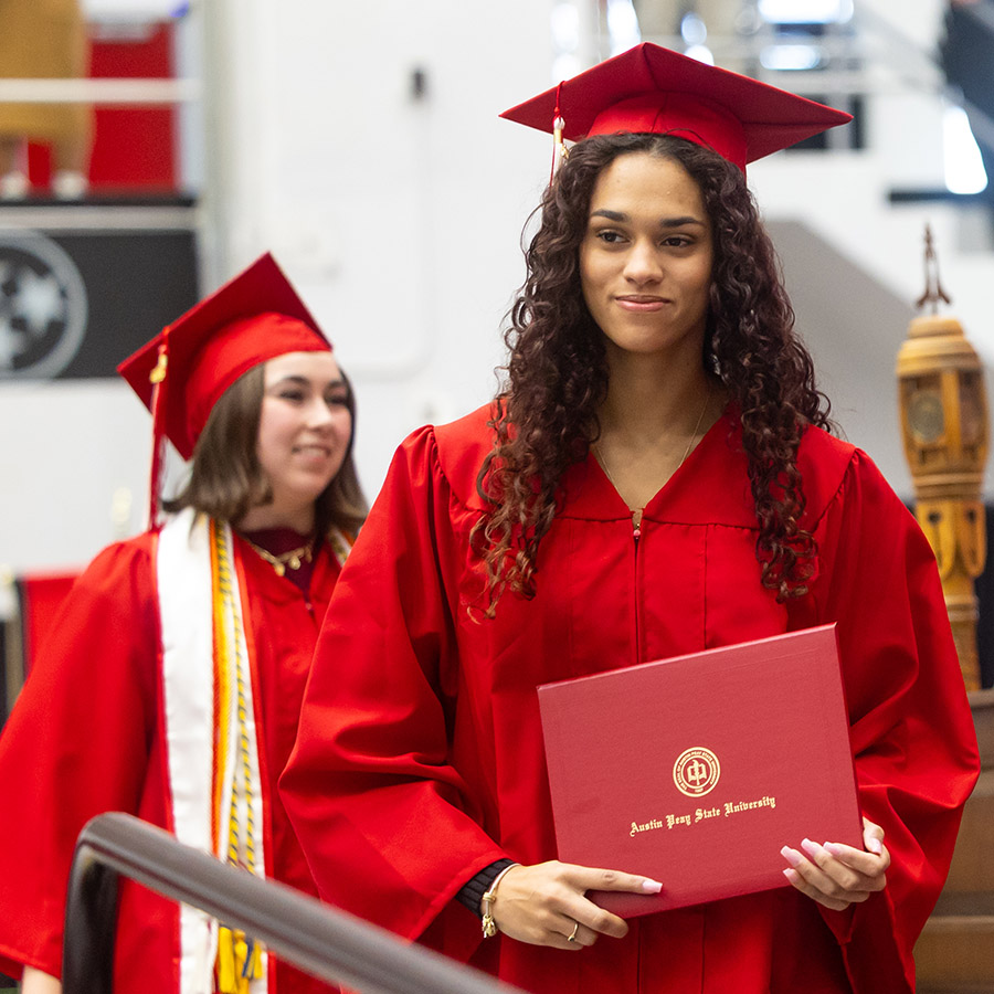 Two Ap gradutes walking across the stage during commencement.