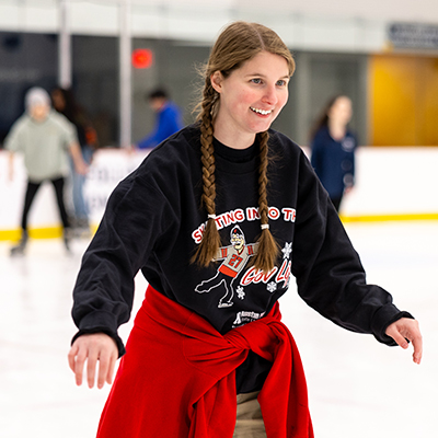 Student ice skating wearing a black 'Skate into the Gov Life' sweatshirt.