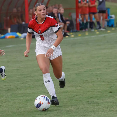 Women's soccer player looking across the field to kick the ball to a team mate.