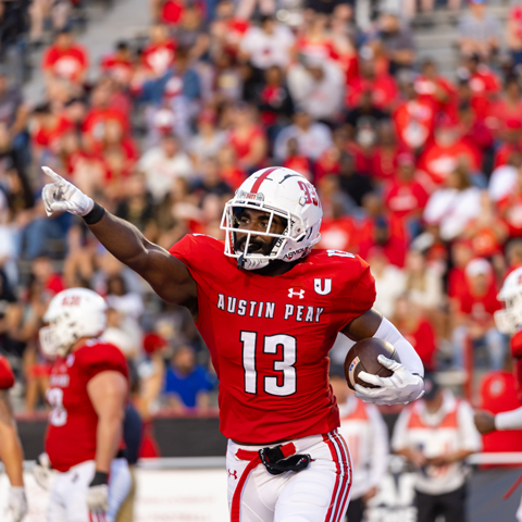 Football player, with the ball, pointing into the crowd after a successful play.