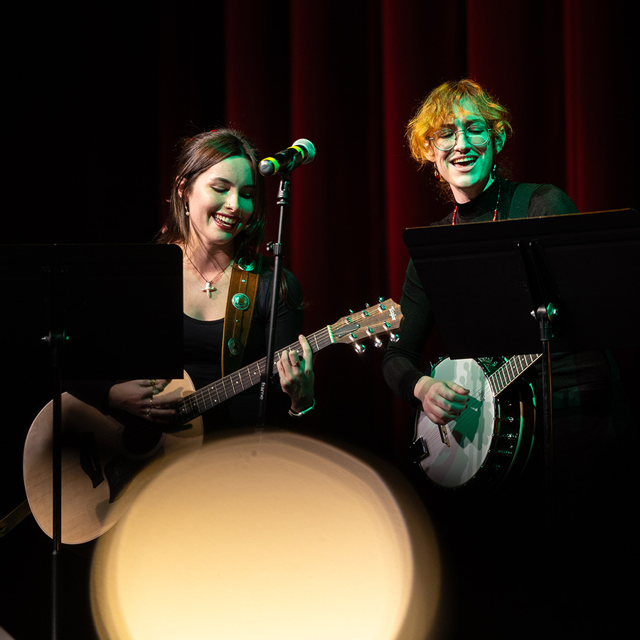 Students on stage playing a guitar and banjo during a music performance.