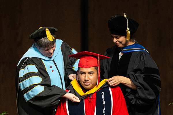 A graduate student being hooded for his graduate degree during a hooding ceremony.