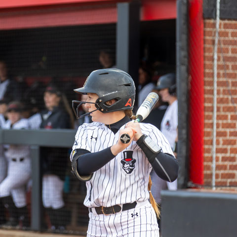 Softball athlete in front of the dugout