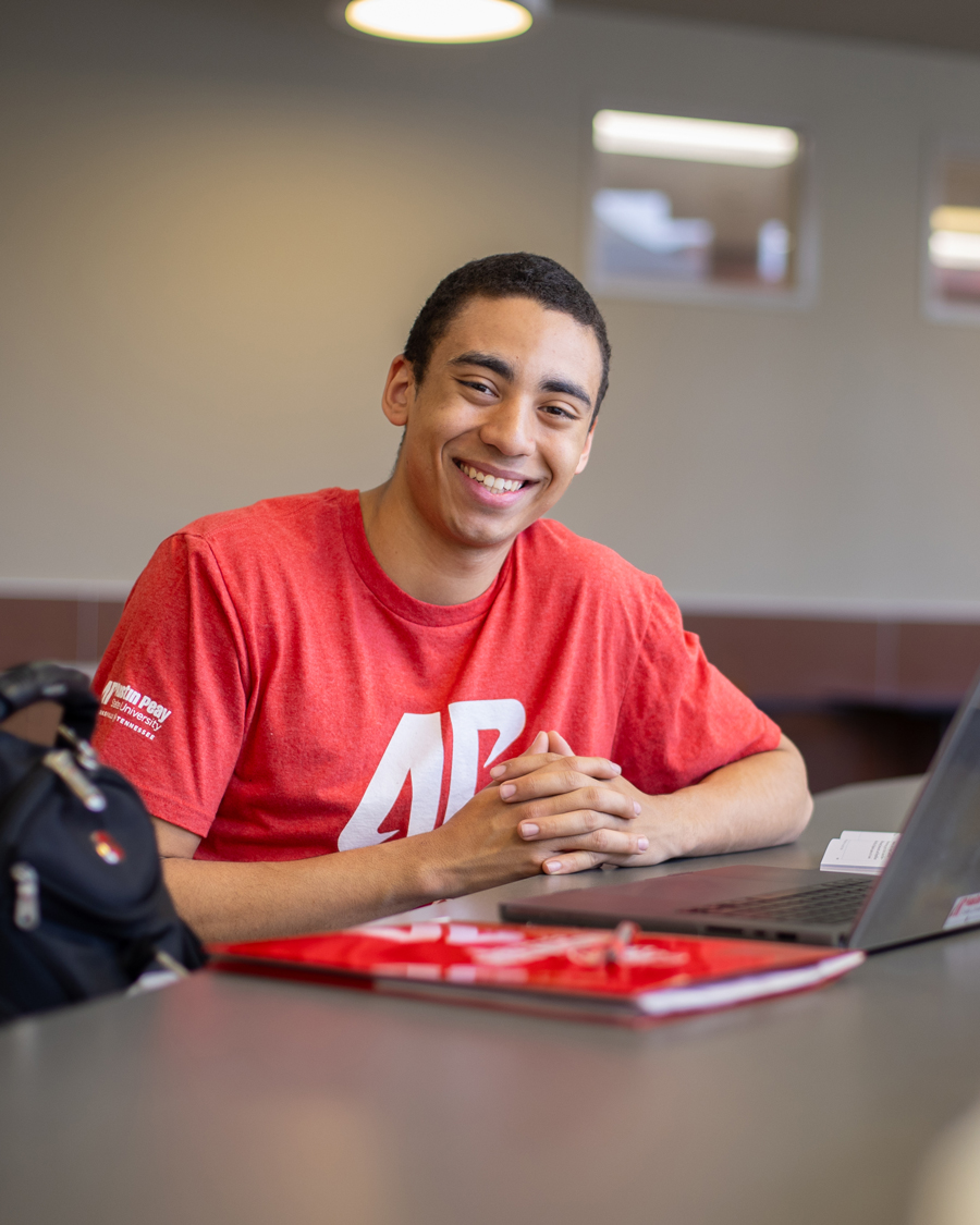 Student sitting infront of their laptop and smiling at the camera