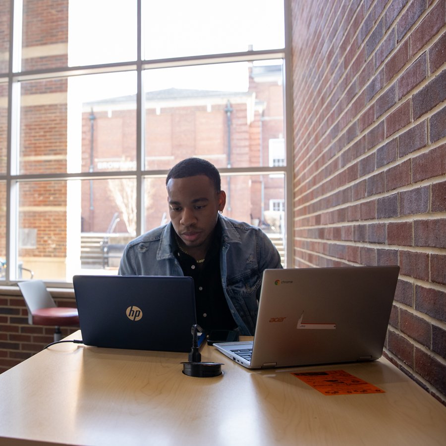 Student at a table with two laptops