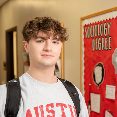 Sociology student in front of bulletin board