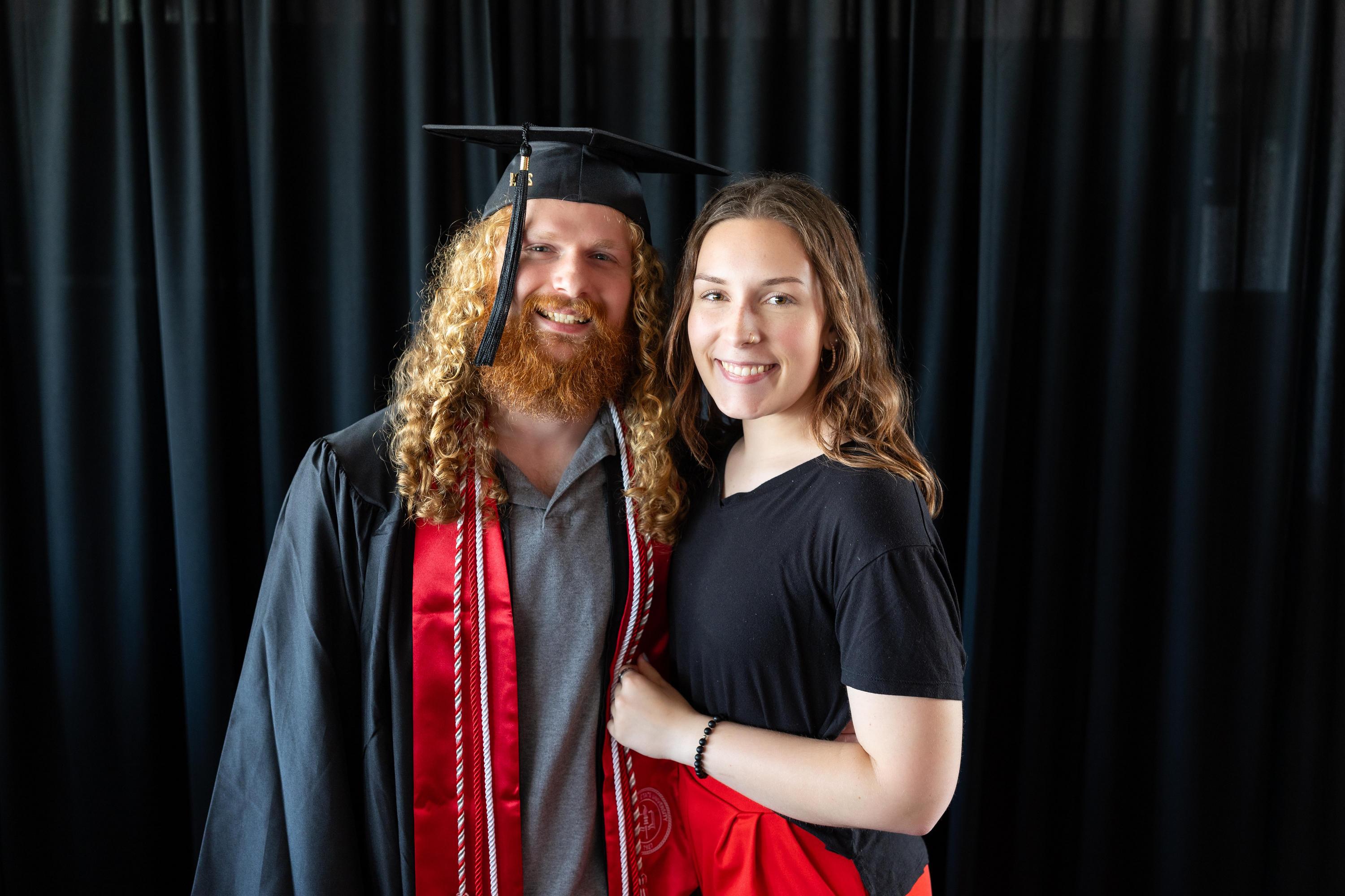 Photo of graduate in cap and gown with partner