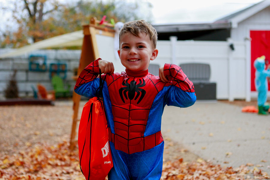 Child dressed as spiderman, showing off their muscles