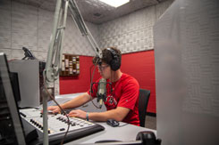 Student sits in communication radio lab