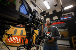 Student operating a camera on a production set for APSU TV