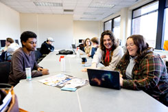 Students sit around a computer working on news pages