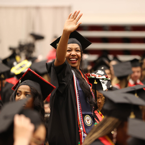 Adult Student waving to the crowd at graduation