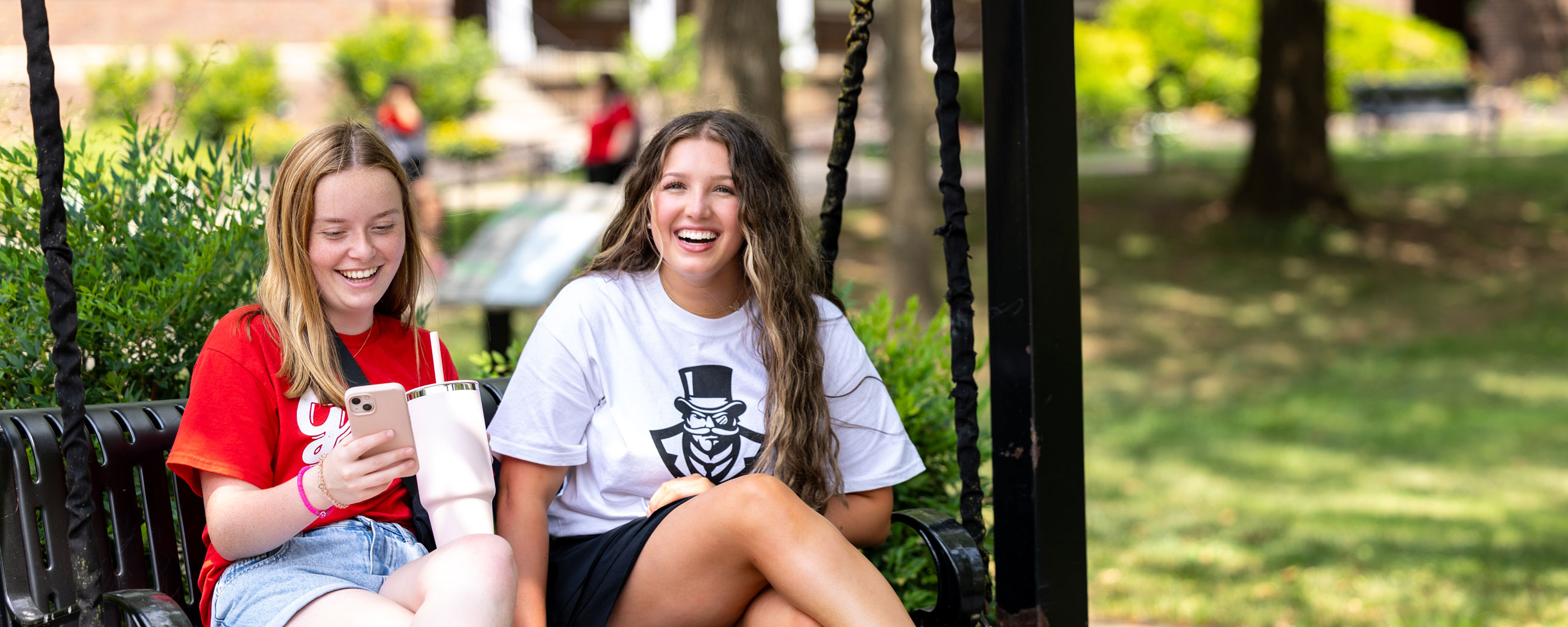 Two Students sitting on an outdoor swing.