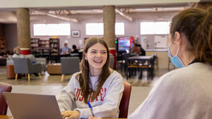 Students talking while one works on a laptop