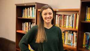 Student standing in front of bookcases full of books