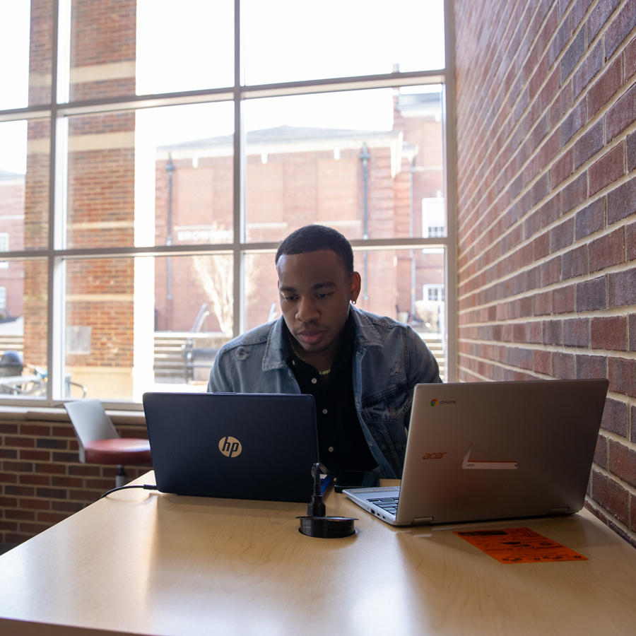 Student sitting in front of two laptops in the University Center