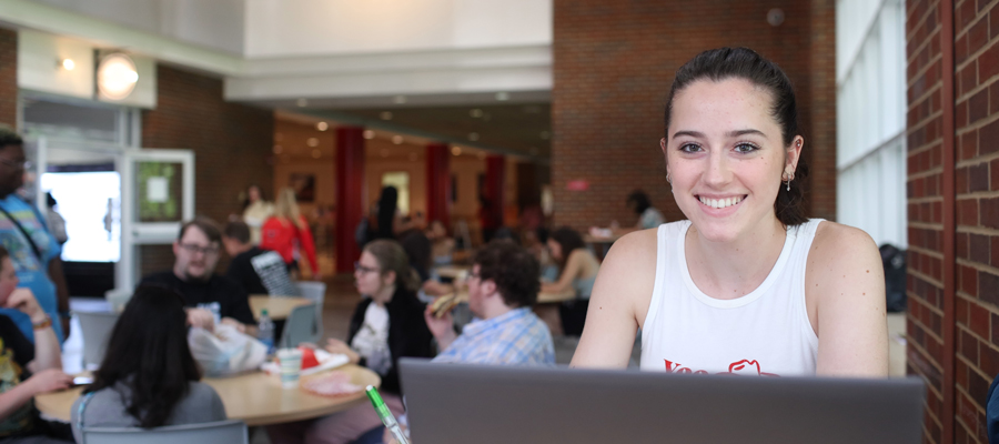 Student in the UC at their laptop with other students in the background