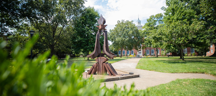 Photo of a statue on the browning lawn that looks like a torch.
