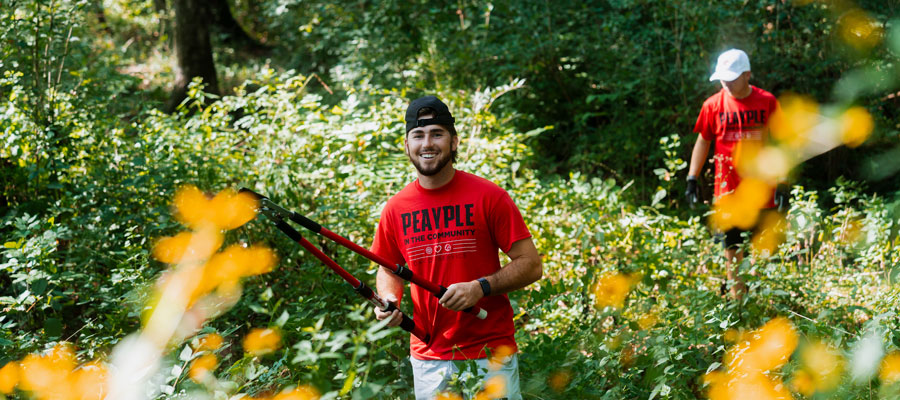 Student hold gardening sheers helping to clean up a walking path as part of Peayple in the Community day service project.