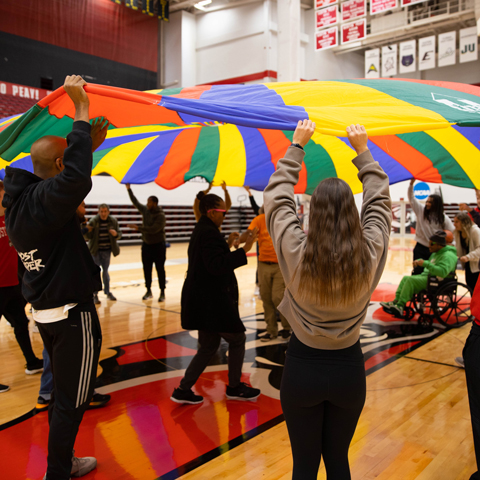 Students working with adults with disabilities in a gym