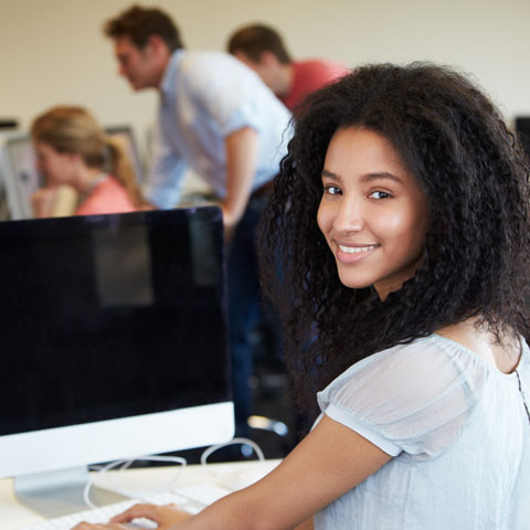 Student sitting at computer, looking back at camera