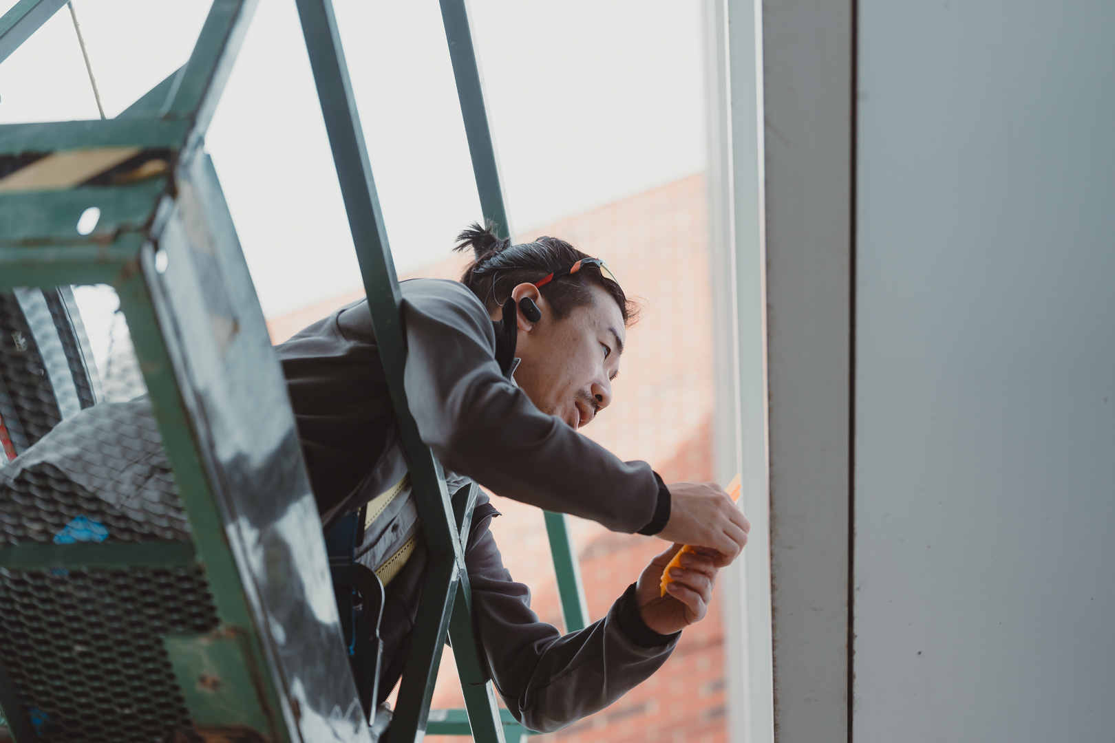 Taro Takizawa works to install a hand-cut vinyl piece at the Art + Design Building.