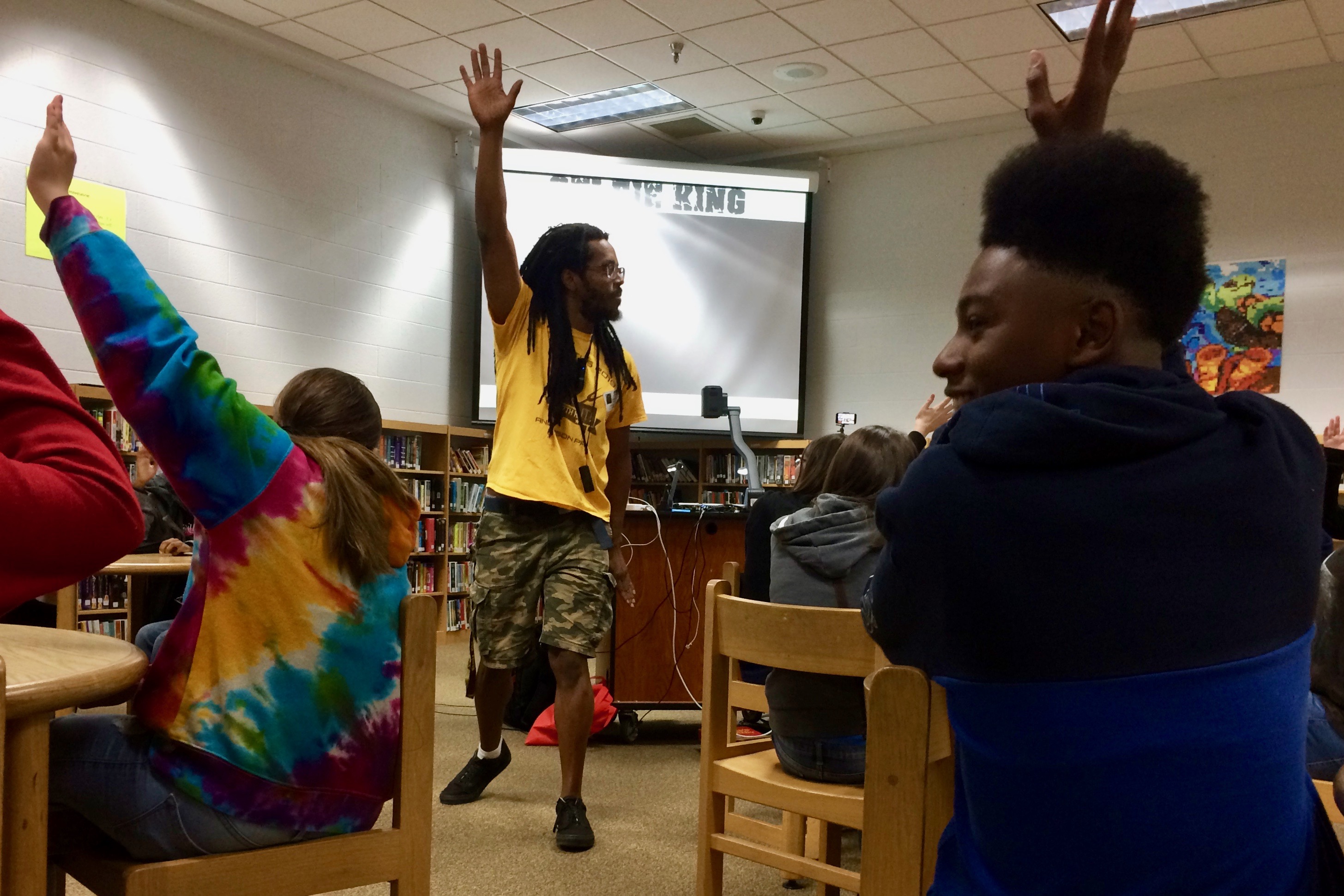 Kennedy Center teaching artist Bomani Armah leads about 60 Kenwood Middle School students in a hip-hop writing exercise. Grabbing the sides of your head and blasting your hands out symbolizes prewriting in Armah’s hip-hop dance.
