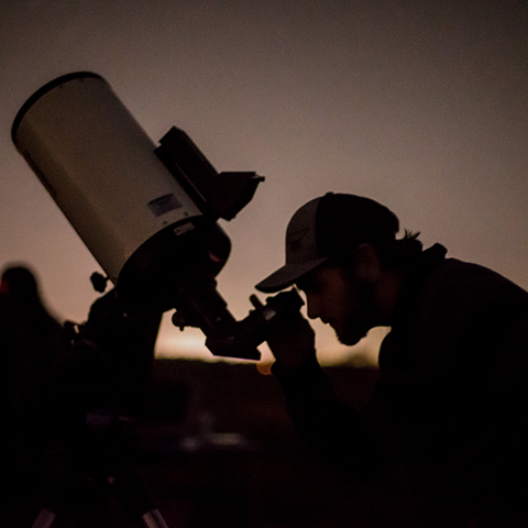 Astronomy student looks through telescope