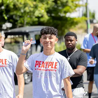 Group of students in their peayple in the community day tshirts walking through a parking lot