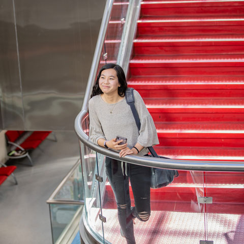 Student standing on the Sundquist stairs looking optimistic.