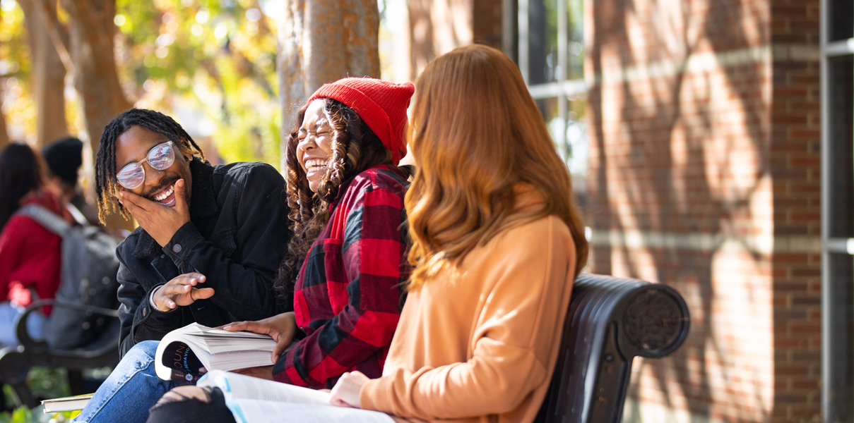 Students talking on a bench outside the UC.