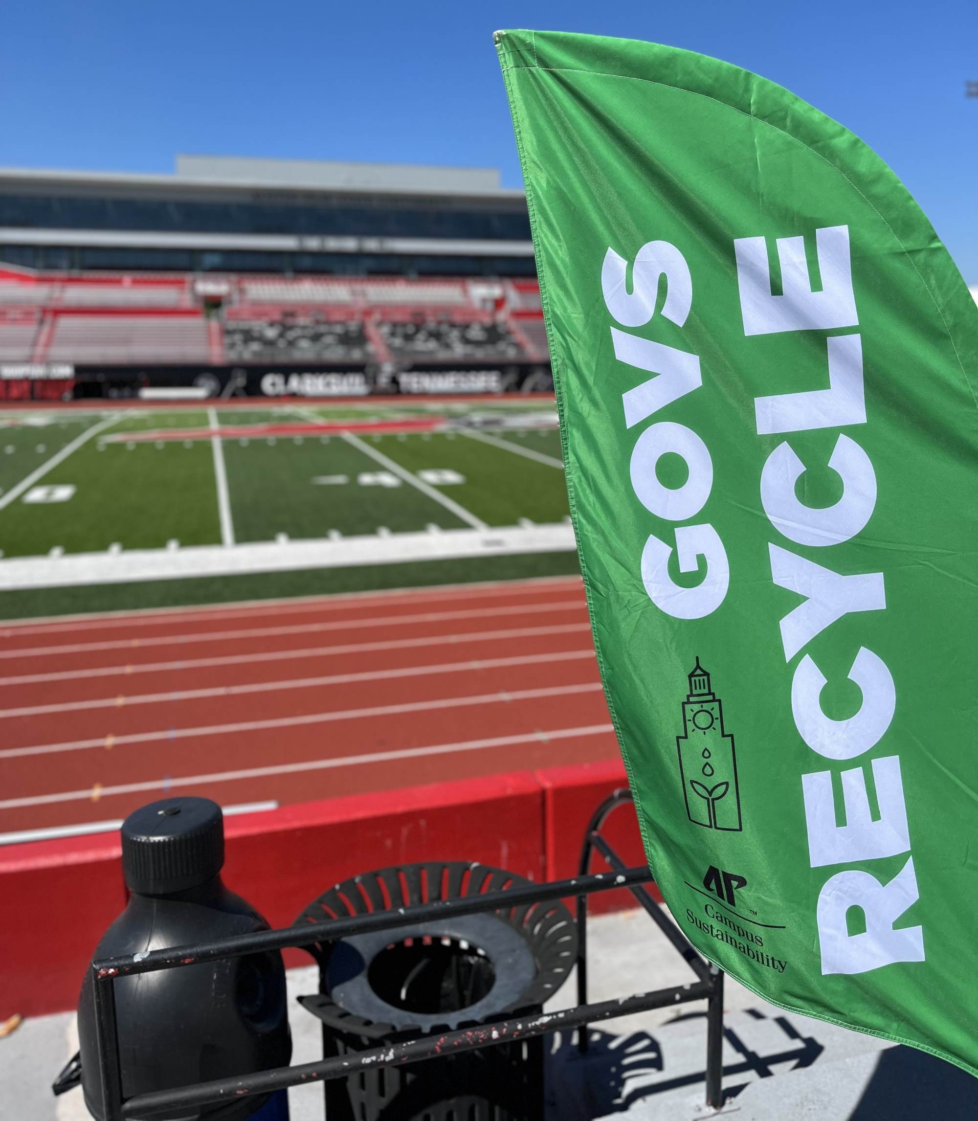 Flag that says govs recycle with the football field in background