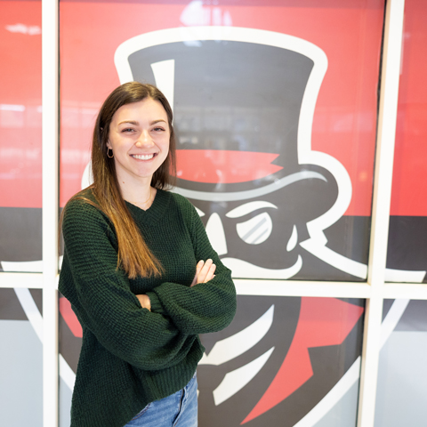 Student smiling in front of the Gov head symbol