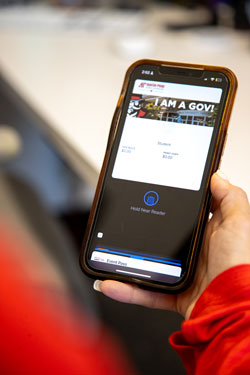 Someone holding up thier smartphone with their Govs ID pulled up on the screen.
