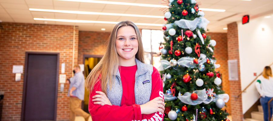 Student in the Kimbrough Lobby infront of a Christmas Tree